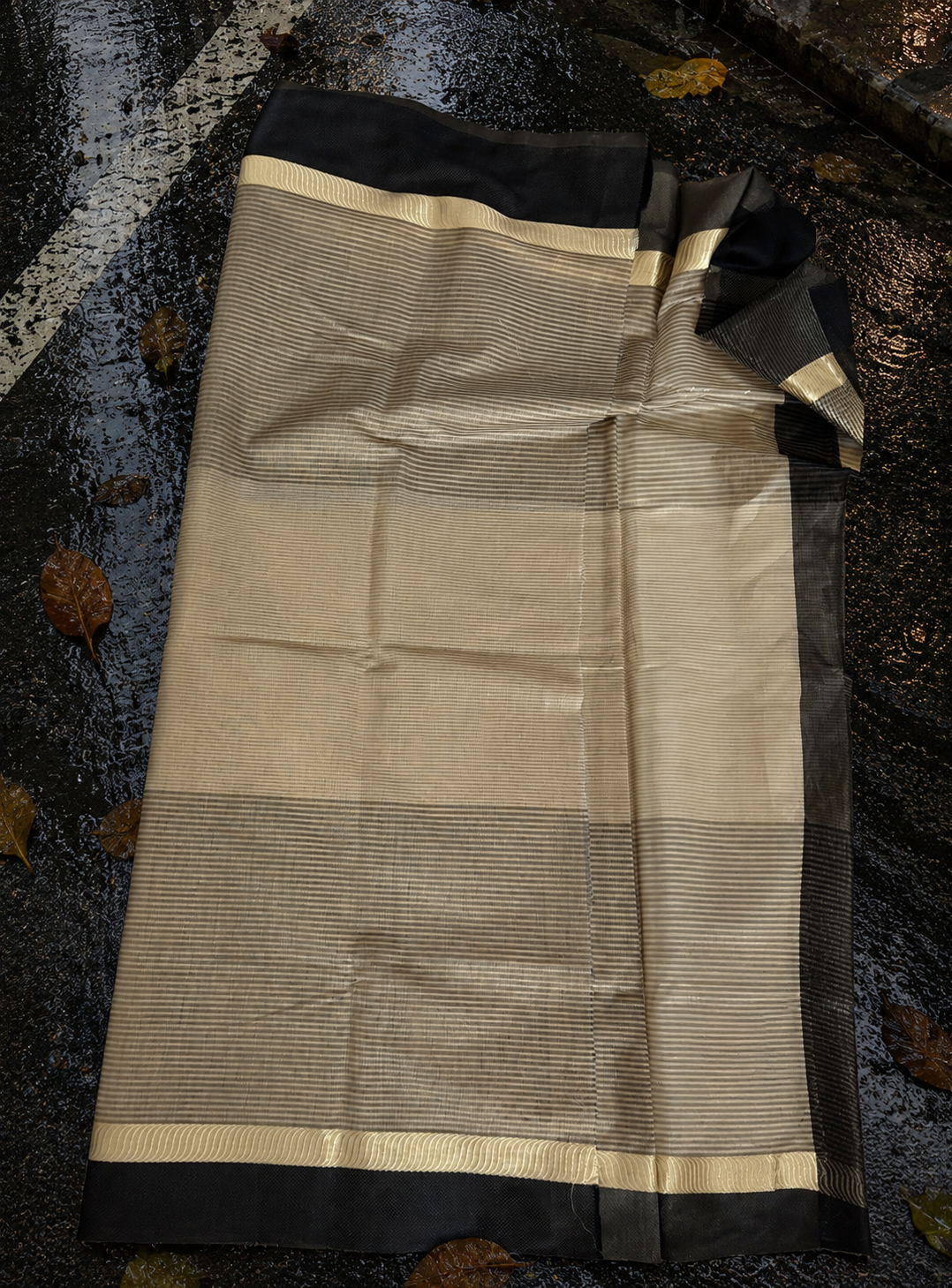 Close-up of beige Chanderi saree highlighting fine woven texture, black border and handcrafted tassel finish.