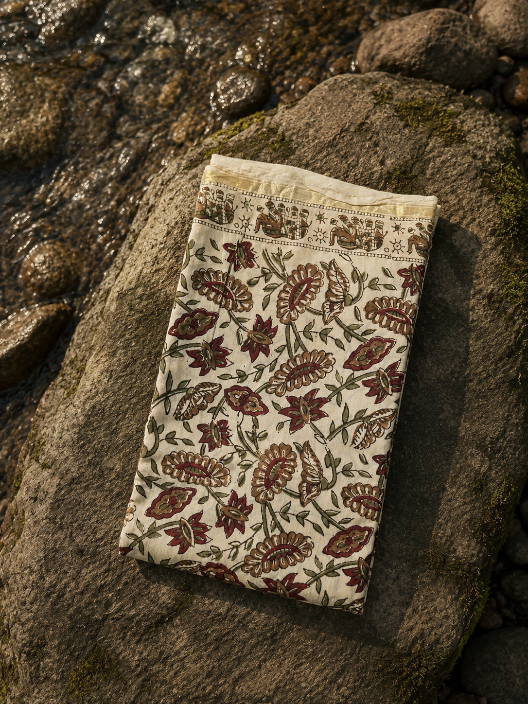 Folded cream Kalamkari hand block printed Chanderi kurta with floral motifs and zari border.