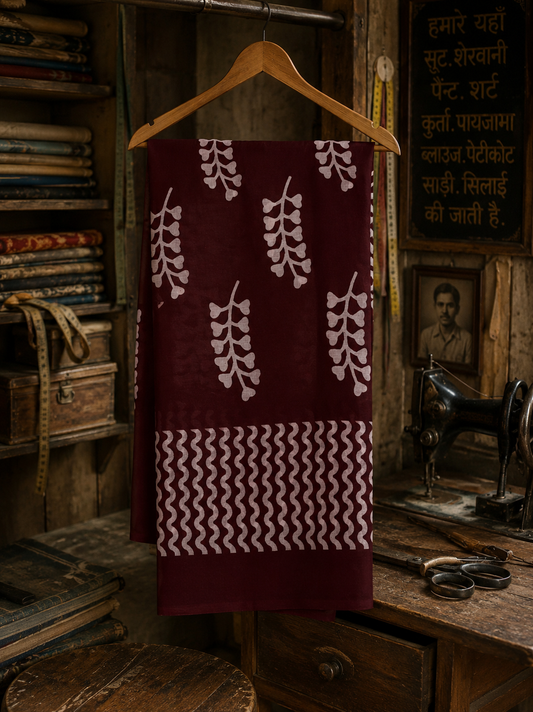 Maroon hand block printed Mul cotton saree featuring traditional botanical motifs hanging on a wooden hanger.